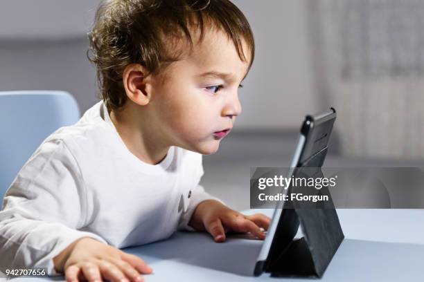kleiner junge eng mit blick auf digital-tablette - schocktaktik stock-fotos und bilder
