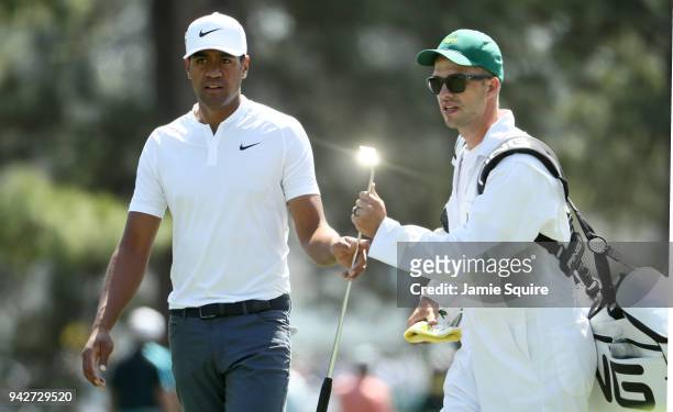Tony Finau of the United States hands a club to caddie Gregory Bodine on the eighth hole during the second round of the 2018 Masters Tournament at...