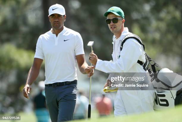 Tony Finau of the United States hands a club to caddie Gregory Bodine on the eighth hole during the second round of the 2018 Masters Tournament at...