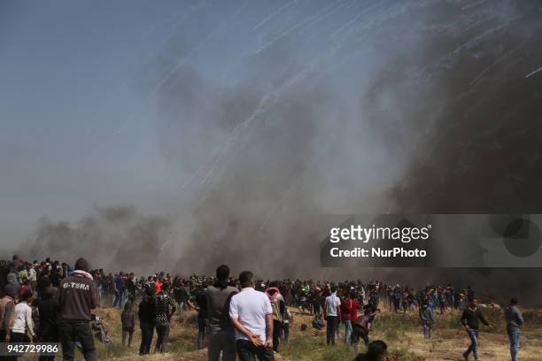 Palestinian men run for cover from tears gas canisters at the Israel-Gaza border during a protest, east of Gaza City in the Gaza strip, on April 6,...