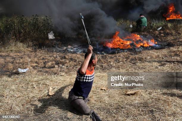 Disabled Palestinian protester hurls stones at Israeli troops during a protest at the Gaza Strip's border with Israel, Friday, April 6, 2018.