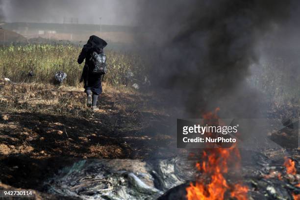 Palestinian woman collects stones for protesters hurling them at the Israeli troops during a protest at the Gaza Strip's border with Israel, Friday,...