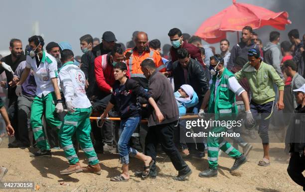 Palestinians carry an injured protestor during clashes with Israeli security forces on the Gaza-Israel border following a protest calling for the...
