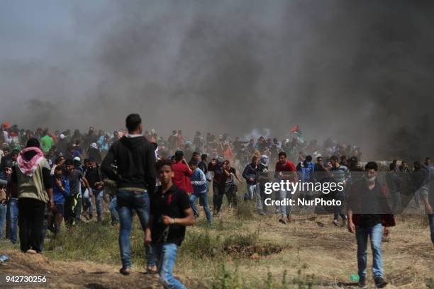 Palestinian men run for cover from tears gas canisters at the Israel-Gaza border during a protest, east of Gaza City in the Gaza strip, on April 6,...