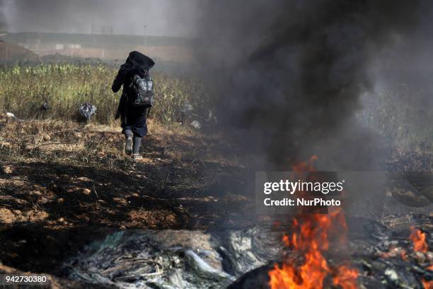 Palestinian woman collects stones for protesters hurling them at the Israeli troops during a protest at the Gaza Strip's border with Israel, Friday,...