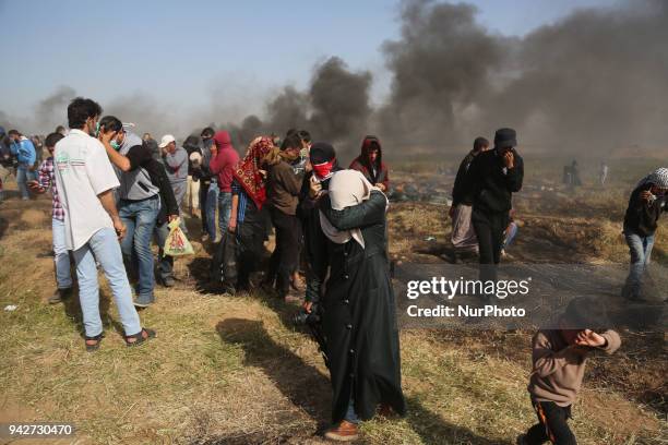 Palestinian men run for cover from tears gas canisters at the Israel-Gaza border during a protest, east of Gaza City in the Gaza strip, on April 6,...