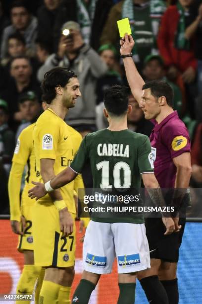 French referee Nicolas Rainville gives a yellow card to Paris Saint-Germain's Argentinian midfielder Javier Pastore next to Saint-Etienne's French...