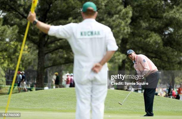 Matt Kuchar of the United States putts on the eighth hole as caddie John Wood looks on during the second round of the 2018 Masters Tournament at...
