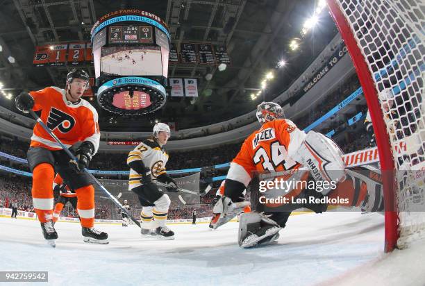 Petr Mrazek and Ivan Provorov of the Philadelphia Flyers react to a shot on goal by Ryan Donato and Torey Krug of the Boston Bruins on April 1, 2018...