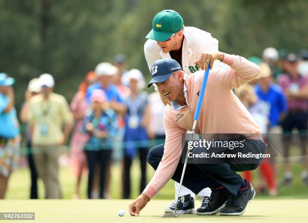 Matt Kuchar of the United States and caddie John Wood line up a putt on the 17th hole during the second round of the 2018 Masters Tournament at...