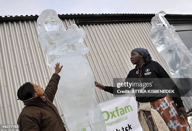 Participants of the UN Climate Change Conference Shorbanu Khetun of Bangladesh and Constance Okollet of Uganda touch the three-meter-high ice...