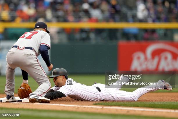 Carlos Gonzalez of the Colorado Rockies beats the tag of third baseman Ryan Flaherty of the Atlanta Braves for a RBI triple in the first inning at...
