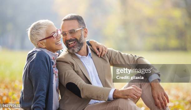 mid aged couple in a park - mid adult stock pictures, royalty-free photos & images