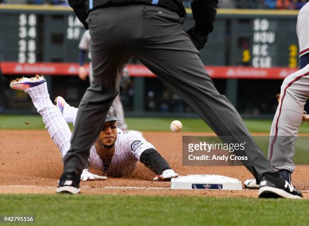 Colorado Rockies right fielder Carlos Gonzalez dives into third base ahead of the tag by Atlanta Braves Ryan Flaherty in the first inning of the...