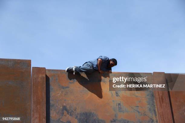 Mexican climbs the metal wall that divides the border between Mexico and the United States to cross illegally to Sunland Park from Ciudad Juarez,...