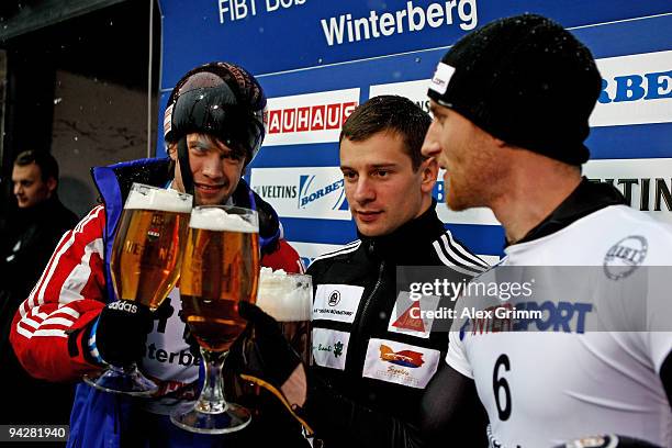 Martins Dukurs of Latvia poses with second placed Frank Rommel of Germany and third placed Alexander Tretiakov of Russia after winning the men's...