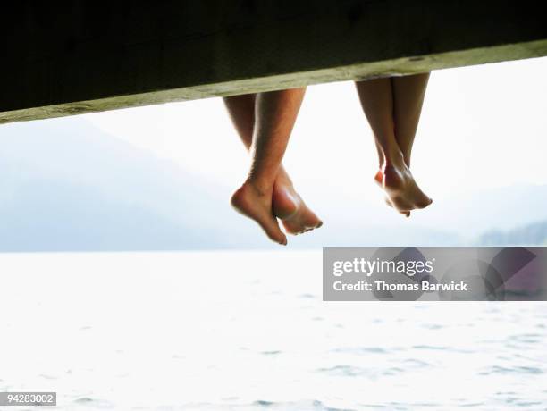 couples feet hanging off dock on lake - girlfriend feet stock pictures, royalty-free photos & images