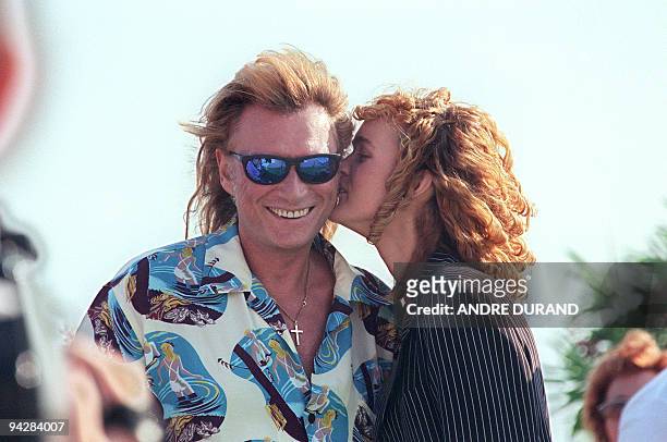 Laeticia, épouse du chanteur de rock et acteur français Johnny Hallyday, embrasse son mari le 22 juin 1996 au Cap d'Agde, où ils passent leurs...