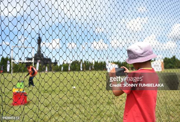 Young boy takes a picture with a mobile phone through the safety fence prior to the start of the FAI Drone Racing World Cup event in Denpasar on...