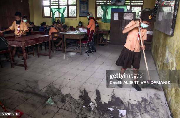 Students clean volcanic ash from their class room after Mount Sinabung volcano spewed thick volcanic ash across the area in the village of Tiga...