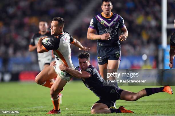 Luke Brooks of the Tigers is tackled by Brodie Croft of the Storm during the round five NRL match between the Wests Tigers and the Melbourne Storm at...