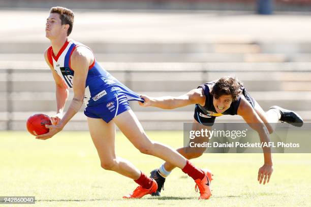 Matthew McGannon of the Power handpasses the ball under pressure from Mitch Goodwin of the Pioneers during the round three TAC Cup match between...