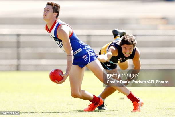 Matthew McGannon of the Power handpasses the ball under pressure from Mitch Goodwin of the Pioneers during the round three TAC Cup match between...