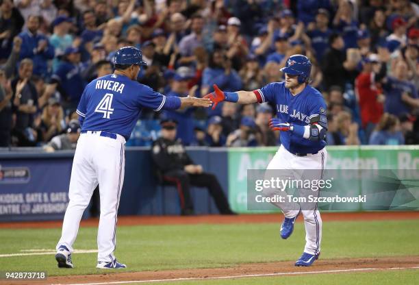 Josh Donaldson of the Toronto Blue Jays is congratulated by third base coach Luis Rivera after hitting a solo home run in the sixth inning during MLB...