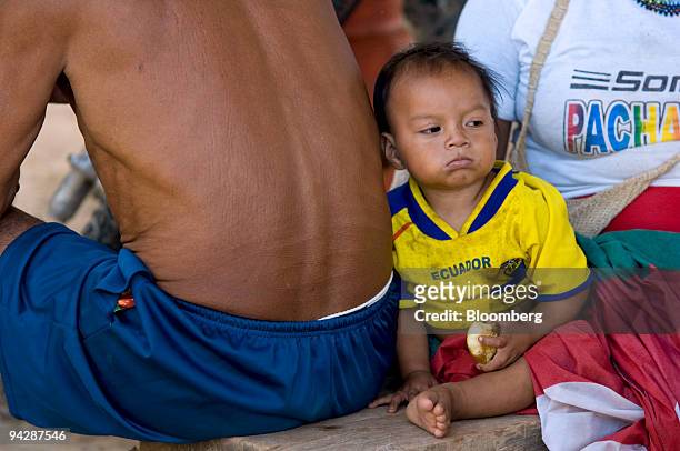 Child from the Huaorani tribe, also known as the Waos, who are native Amerindians from the Amazonian Region of Ecuador, sits with his parents in...