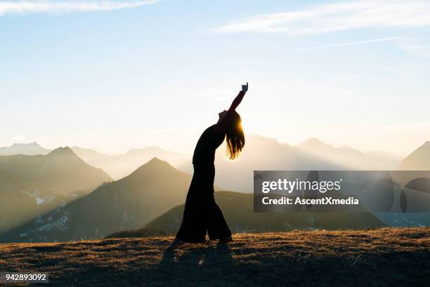 frau tanzt bei sonnenaufgang in den bergen - peaceful nature stock-fotos und bilder