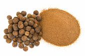 Pile of ground and whole allspice on white
