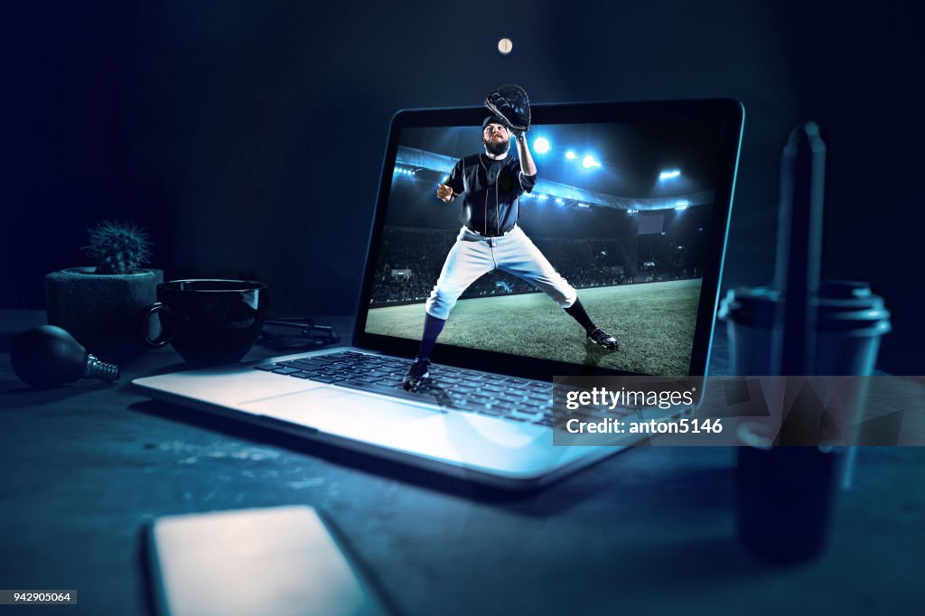 The one caucasian man as baseball player playing against stadium on the laptop. Collage