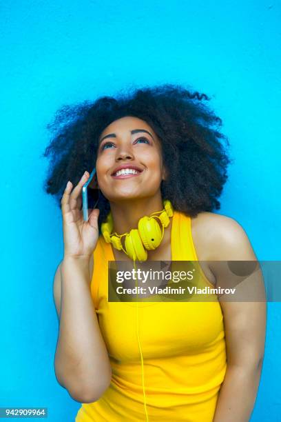 afrikaanse vrouw plezier en praten over de telefoon - fashion pretty woman listening music in headphones with smartphone colorful stockfoto's en -beelden