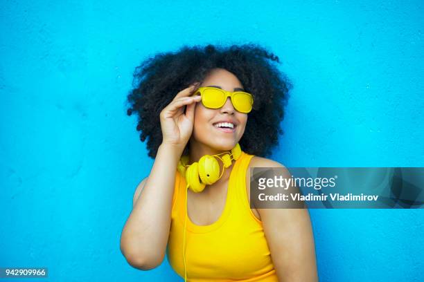 femme africaine sans soucis en tenue jaune - fashion pretty woman listening music in headphones with smartphone colorful photos et images de collection