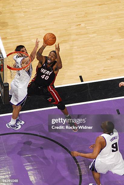 Udonis Haslem of the Miami Heat goes up for a shot against Omri Casspi and Kenny Thomas of the Sacramento Kings during the game at Arco Arena on...