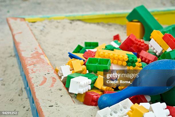 child's wooden sandbox piled with multicolored plastic block pieces - zandbak stockfoto's en -beelden