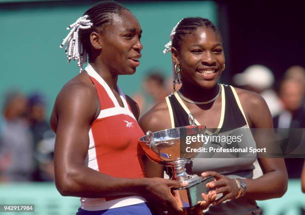 Sisters Venus Williams and Serena Williams of the USA pose with the trophy after defeating Martina Hingis of Switzerland and Anna Kournikova of...