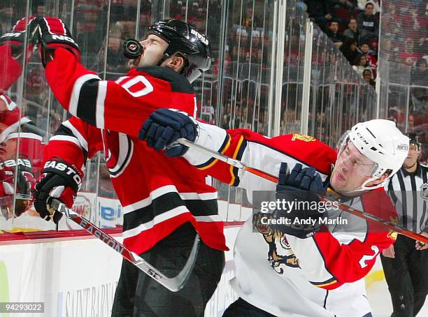 Rod Pelley of the New Jersey Devils is hit in the face with the puck while being checked by Keith Ballard of the Florida Panthers during their game...