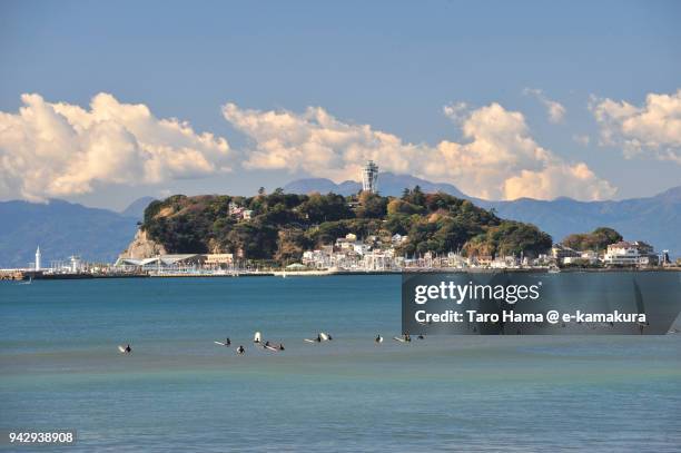 clouds on izu peninsula and enoshima island, and many surfers on sagami bay, northern pacific ocean in japan - enoshima island stock pictures, royalty-free photos & images