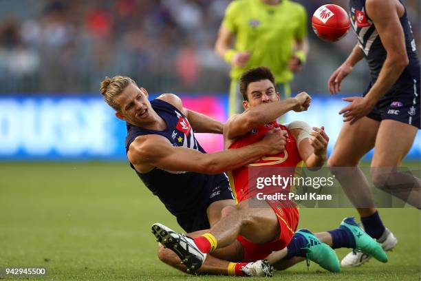 Jarryd Lyons of the Suns gets his handball away while being tackled by Nathan Fyfe of the Dockers during the round three AFL match between the Gold...