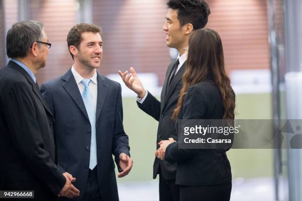 caucasian businessman discussing in the corridor with asian colleagues - translator stock pictures, royalty-free photos & images