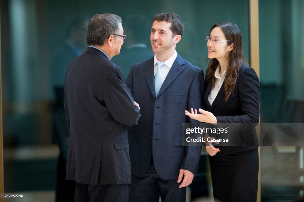 Caucasian businessman with his interpreter discussing a deal with senior Asian businessman