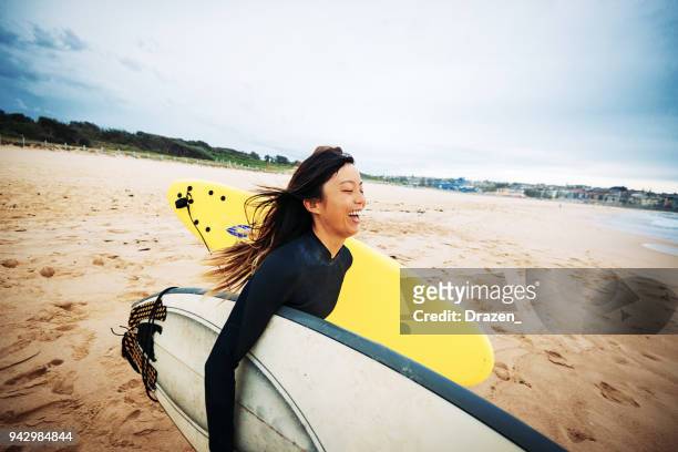 surfen is uitstekende fysieke activiteit - asian surfer stockfoto's en -beelden
