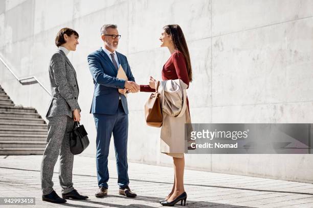 gens d’affaires se serrant la main contre le mur - homme rencontre femme photos et images de collection