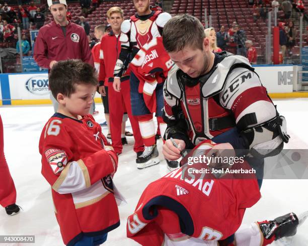 Mark Pysyk of the Florida Panthers signs his jersey for a young fan during the "shirts off our back" promotion after the game against the Boston...