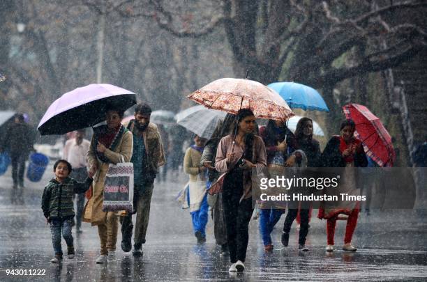 People walking with umbrellas during rain at Ridge, on April 7 2018 in Shimla, India.