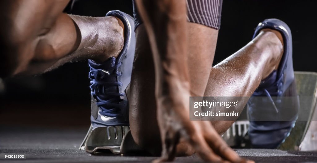 Male sprinter taking his position on starting blocks
