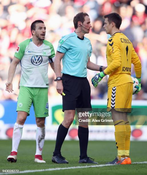 Referee Sascha Stegemann discusses with goalkeeper Alexander Schwolow of Freiburg and Ignacio Camacho of Wolfsburg during the Bundesliga match...