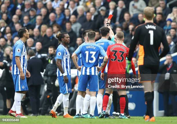 Davy Propper of Brighton and Hove Albion is shown a red card by referee Anthony Taylor during the Premier League match between Brighton and Hove...