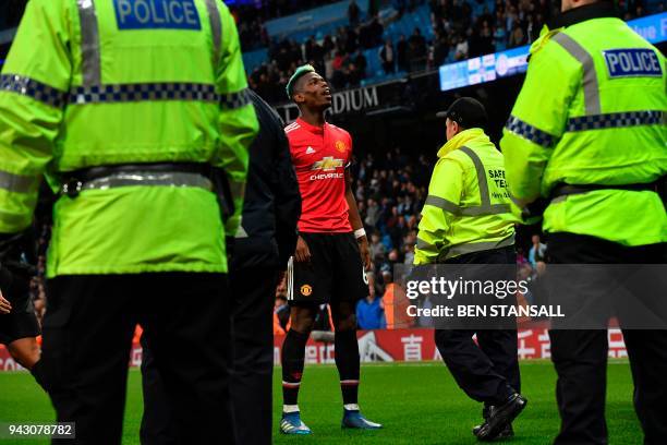 Manchester United's French midfielder Paul Pogba celebrates victory surrounded by security and police after the final whistle in the English Premier...